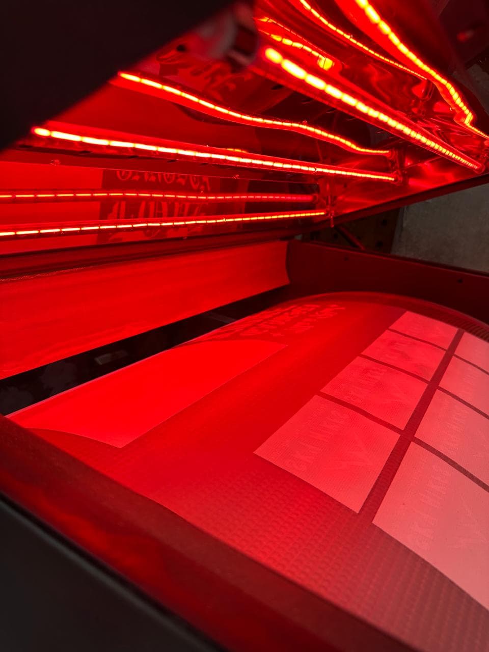 Interior of a red light therapy bed with rows of glowing red LED strips.
