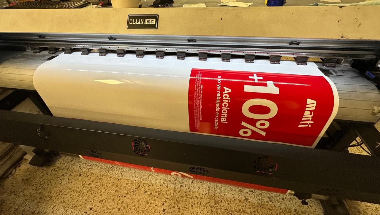 Large-format printer producing a red promotional banner for Martí with a 10% discount message.